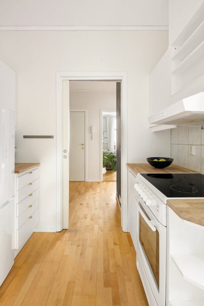 Bright and modern kitchen interior with white cabinets and wooden flooring, perfect for urban living.