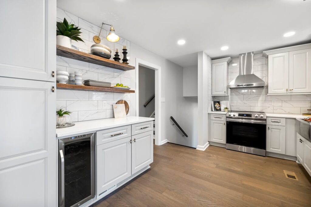 Stylish modern kitchen with white cabinets, wooden shelves, and stainless steel appliances.