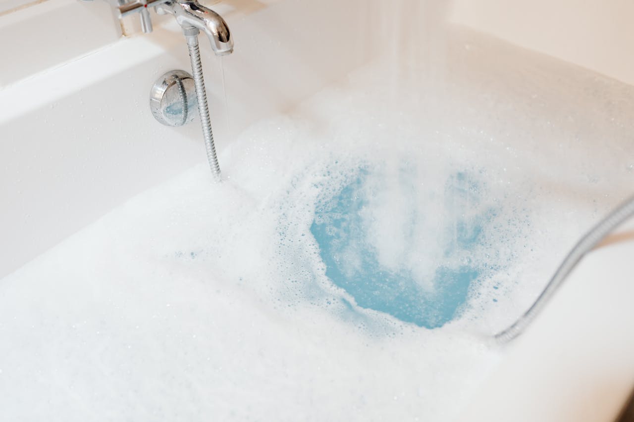 A white bathtub being filled with water and bubbles, creating a relaxing ambience.